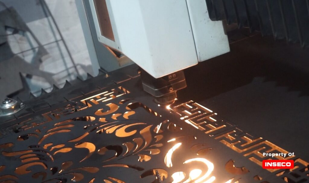 Mesin laser cutting plat besi sedang beroperasi, memotong plat besi dengan presisi tinggi dan detail yang rapi