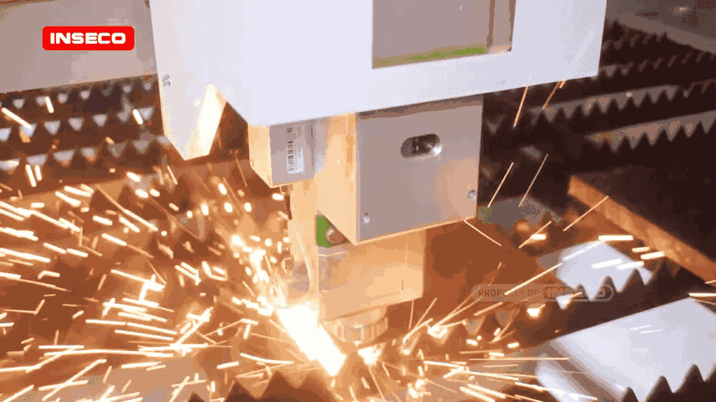 Tampak dekat kepala laser Raytools INSECO saat memotong plat baja, memercikkan cahaya dan bunga api terang.
